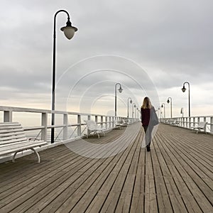 Solitary young woman walking on pier