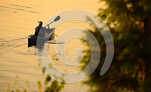 Solitude concept with man alone in a lake during sunrise or sun