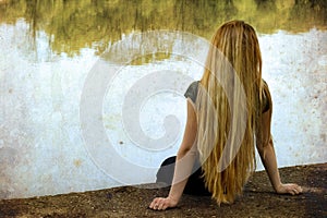 Solitude - lonely woman sitting on lake side