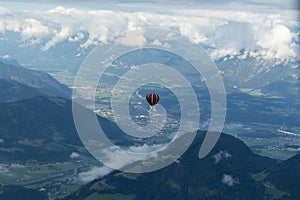 Soll, Tirol/Austria - September 25 2018: A hopper hot-air balloon in the distance above the mountains and above the clouds