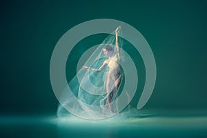 Solo. Beautiful and graceful ballet dancer dancing with white transparent cloth, isolated on cyan color background. Art
