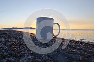 A solo blank coffee mug on the shorline