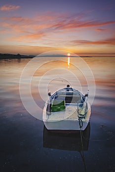 Solo boat on sunset red clouds and sun