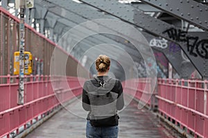 Solo casual woman walking the cycling lane on Williamsburg Bridge, Brooklyn, New York City, USA