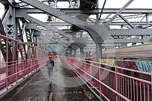 Solo casual woman walking the cycling lane on Williamsburg Bridge, Brooklyn, New York City, USA