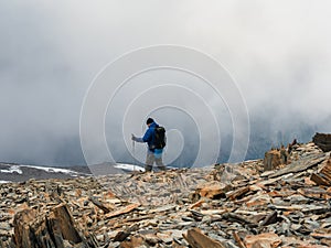Solo climbing. Activities man climb to the top of a misty stone hill. People in difficult conditions. Foggy day in the mountains.