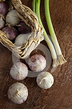 Solo Garlic in a Small Basket and Green Onions on Old Wood