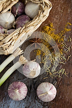 Solo Garlic in a Small Basket with Green Onions and Spices on Old Wood