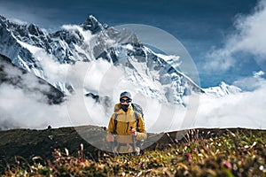 Solo hiker exploring high altitude sunny mountains. Outdoor tourist wearing mountain equipment walking across huge massive rocky