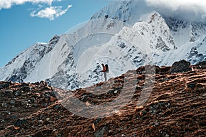 Solo hiker exploring high altitude sunny mountains. Outdoor tourist wearing mountain equipment walking across huge massive rocky