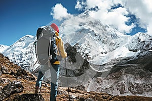 Solo hiker exploring high altitude sunny mountains. Outdoor tourist wearing mountain equipment walking across huge massive rocky