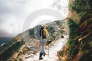 Solo hiker wearing professional walk across foggy mountain. Young tourist traveling along rocky track