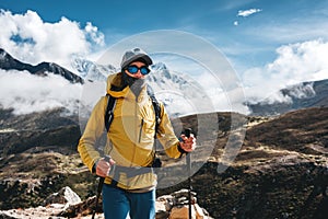 Solo outdoor traveler walk across huge mountains massif wearing yellow jacket and travel backpack. Adventure tourist going along