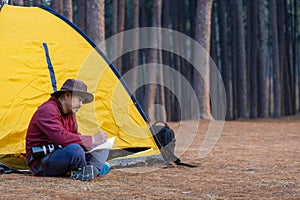 Solo overnight camping while sitting beside tent at campsite in the pine forest while writing journal for freedom, solitude,