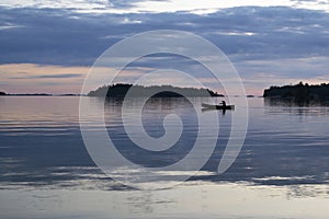 Solo paddling a canoe at dusk in Thirty-Thousand Islands, Ontario
