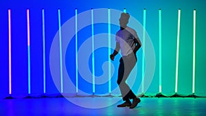 Solo performance by a professional ballroom dancer. Black man dancing salsa against the background of multi-colored neon