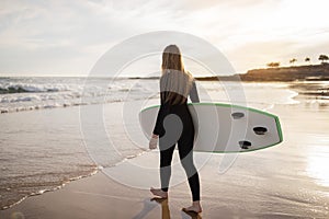 Solo Surfer. Young Woman In Wetsuit Carrying Surfboard Going Into Ocean