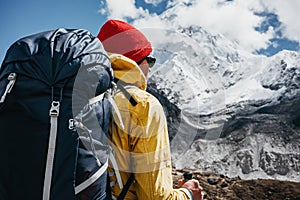 Solo tourist with travel backpack walk along high altitude mountain track. Outdoor mountains explorer traveling among snowy summit