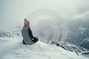 solo traveler meditating on snowcovered mountaintop