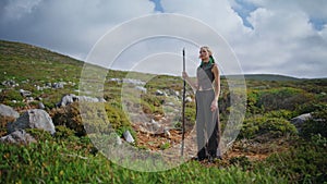 Solo traveler trekking green hillside on summer day. Adventure woman posing