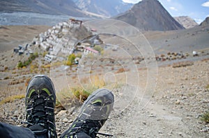 A solo traveler with trekking shoes with the Key Monastery in the background