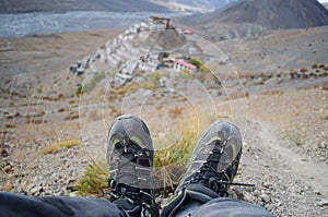 A solo traveler with trekking shoes with the Key Monastery in the background