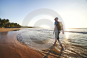 Solo traveler walking on empty beach against beautiful coast at sunrise