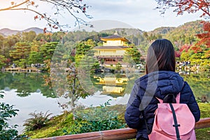 Solo woman tourist trveling at Kinkakuji temple or the golden pavilion in Autumn season, Asian traveler visit in Kyoto, Japan.