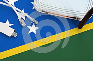 Solomon Islands flag depicted on table with internet rj45 cable, wireless usb wifi adapter and router. Internet connection concept