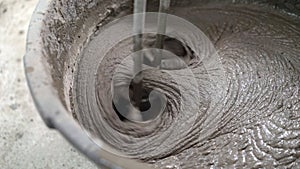 The solution in the bucket is mixed using a construction mixer. Mixing plaster solution in a bucket using electric drill.