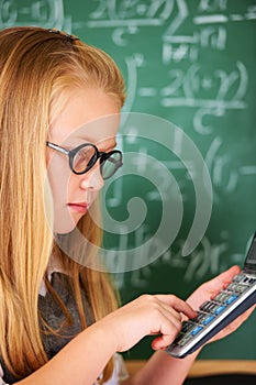 Solving complex math problems. A cute blonde girl using her calculator in class.