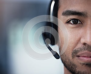 Solving problems one at a time. a young customer service agent sitting alone in the office and wearing a headset.