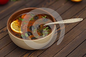Solyanka soup with lemon, meat, pickles, tomato sauce and olives Traditional Russian dish solyanka.