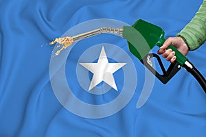 SOMALIA flag Close-up shot on waving background texture with Fuel pump nozzle in hand. The concept of design solutions. 3d