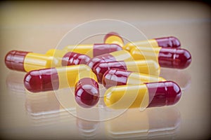 Some aligned red and yellow capsules isolated on brown background