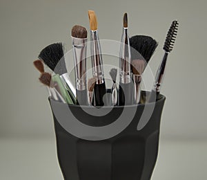 Various facial makeup brushes in a glass