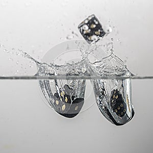 some black game dice drop in water with a splash