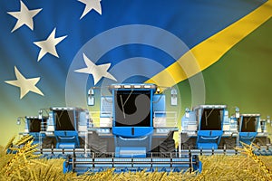 Some blue farming combine harvesters on farm field with Solomon Islands flag background - front view, stop starving concept -