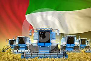 Some blue farming combine harvesters on wheat field with United Arab Emirates flag background - front view, stop starving concept