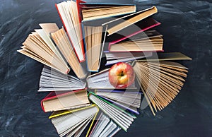 Some books and red apple on the desk over the blackboard