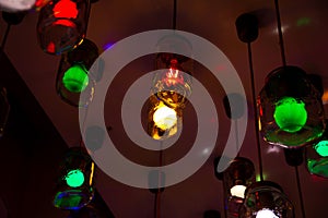 Some ceiling lights that consists of hanging glass jars with red and green colored light bulbs inside