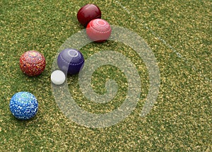 Some colored lawn bowls clustered around the jack