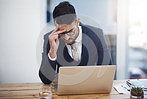 Some days are just a struggle to get through. a young businessman looking stressed out while working in an office.