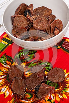 Some dehydrated beef testes for dogs in white bowl and vibrant clothes.
