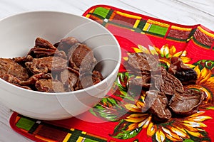 Some dehydrated beef testes for dogs in white bowl and vibrant clothes.