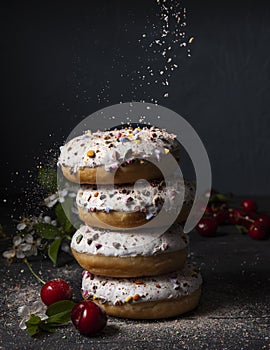 Some delicious donuts at each other with cherry berry on dark background colorful sprinkles front