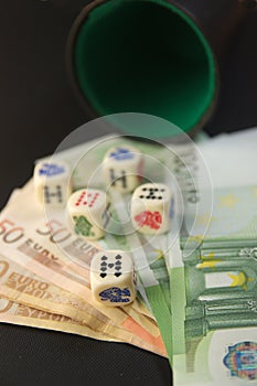 Some euro bills next to poker dice on a game table