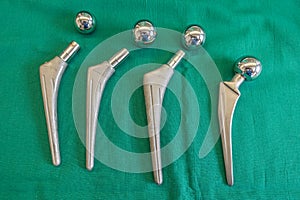 Some explanted hip prostheses lie spread out on a green surgical drape