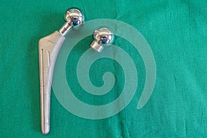 Some explanted hip prostheses lie spread out on a green surgical drape