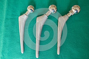 Some explanted hip prostheses lie spread out on a green surgical drape